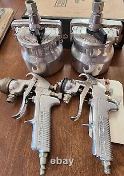Deux pistolets de pulvérisation de peinture DeVilbiss JGA 503 et 502 ainsi que 2 bidons DeVilbiss